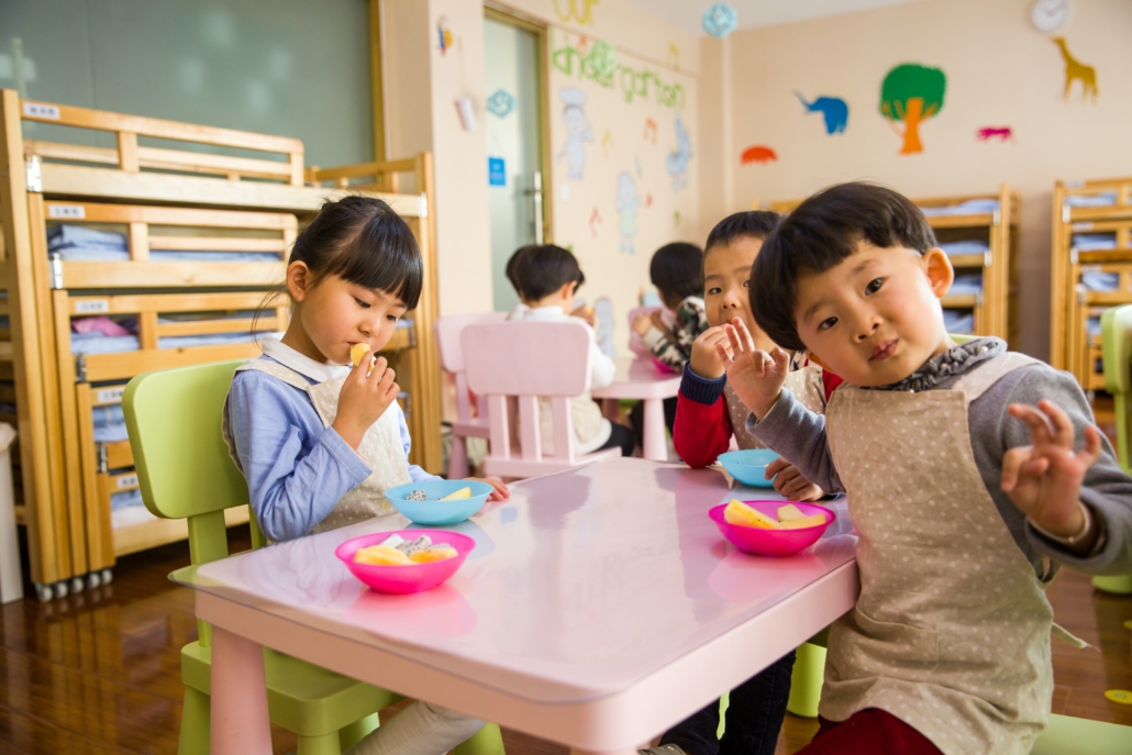 Toddlers eating a snack at a small table