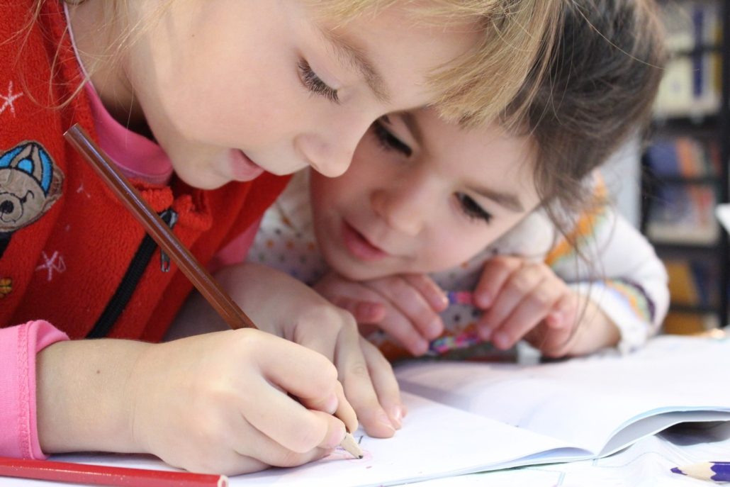 Two children practicing writing, benefiting from Missouri child care assistance